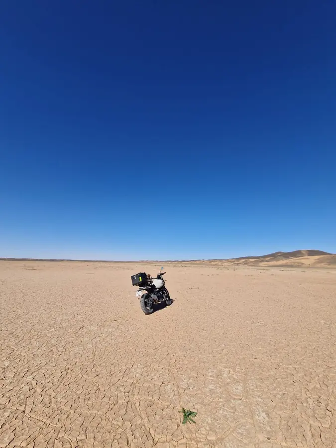 Motorcycle crossing a wide Moroccan desert landscape